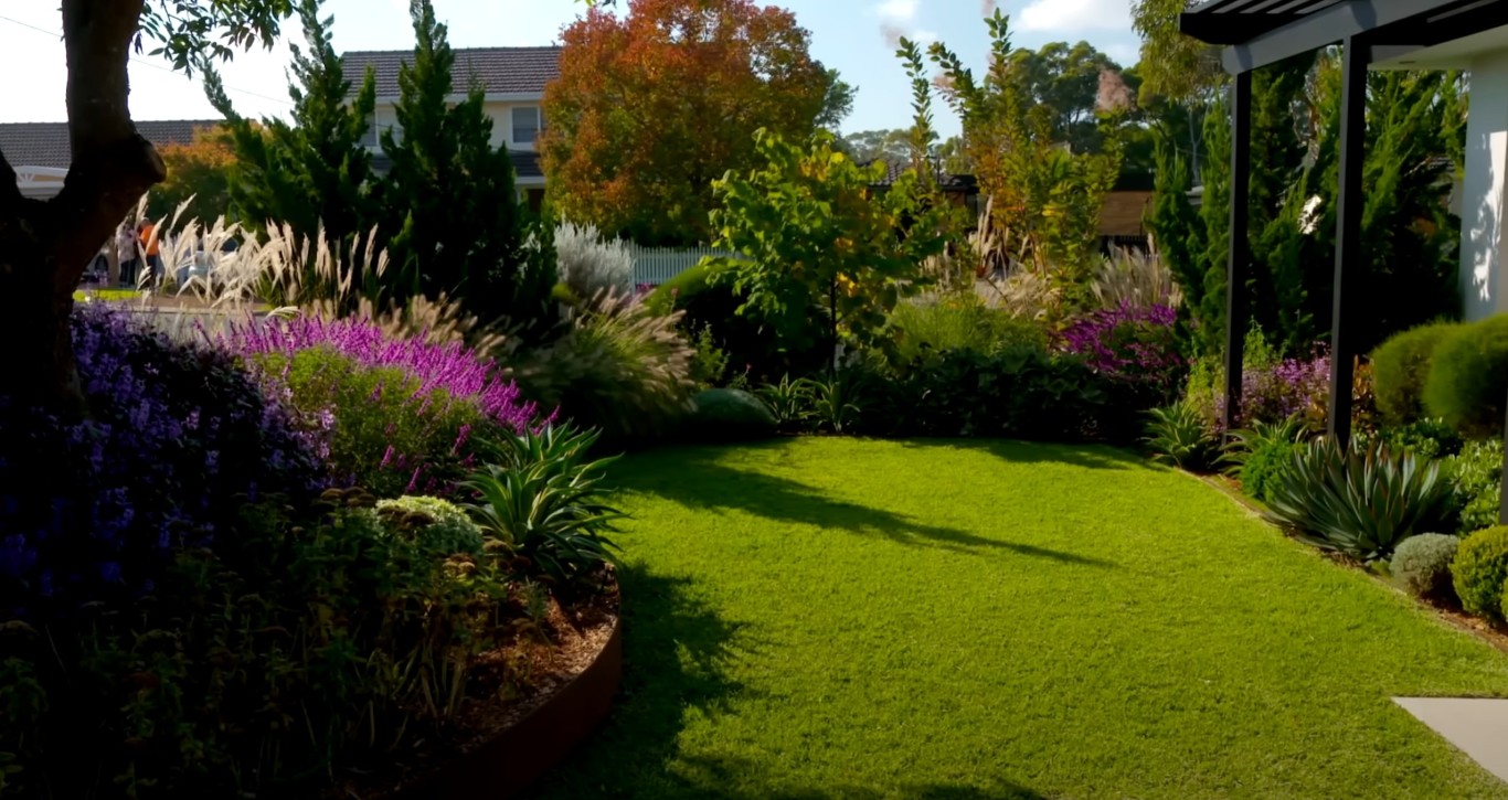 Professional landscaping services showing a lush green lawn with vibrant purple and yellow flowers in Lake Forest, CA